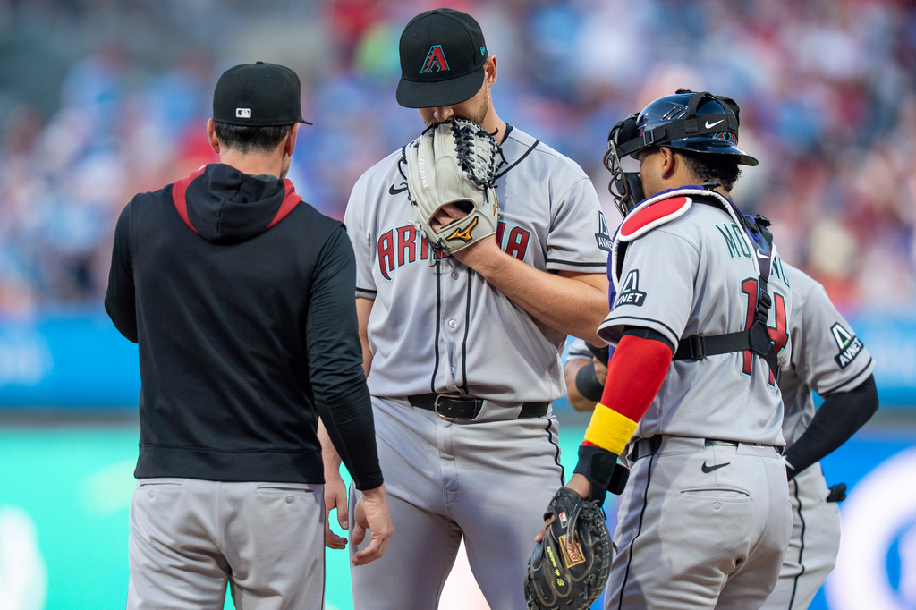 Arizona Diamondbacks starting pitcher Mike Soroka, center, looks down as pitching coach Brian Kaplan, left, and catcher Gabriel Moreno, right, come out to talk to him after the three-run home run by Philadelphia Phillies' Brandon Marsh during the first inning of a baseball game, Friday, April 10, 2026, in Philadelphia. (AP Photo/Chris Szagola)