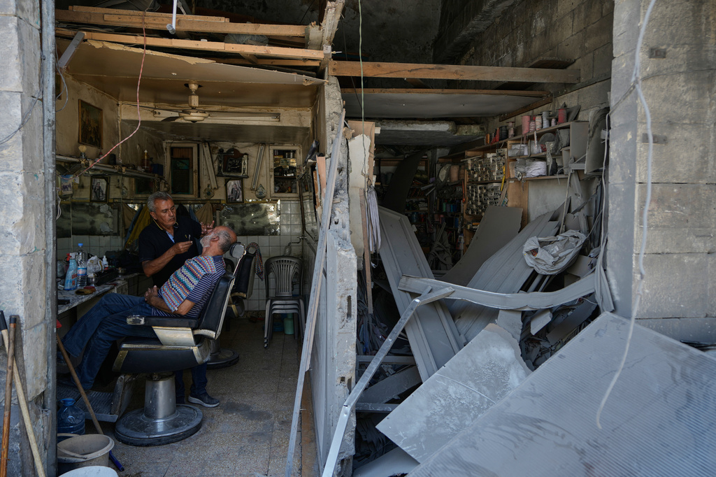 Barber Ali Sbouri grooms a client's beard inside his shop damaged in previous Israeli airstrikes in the town of Nabatiyeh, southern Lebanon, Wednesday, June 24, 2026, after a ceasefire between Israel and Hezbollah. (AP Photo/Bilal Hussein)