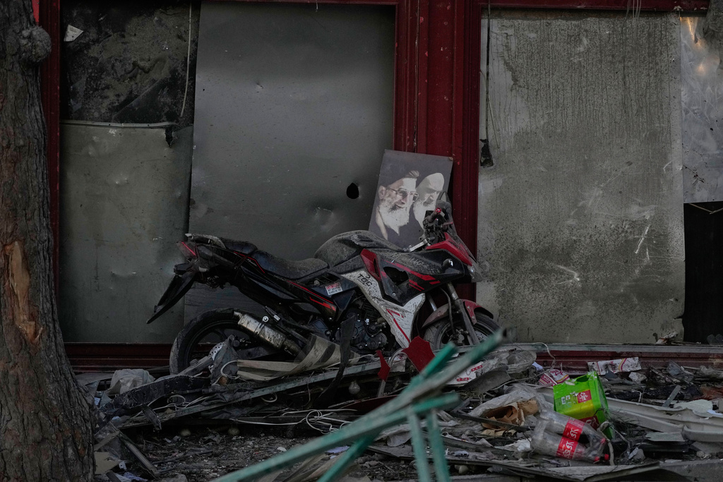 A poster of the late Supreme Leader Ayatollah Ali Khamenei, who was killed during the ongoing joint U.S.-Israeli military campaign, and the late Iranian Revolutionary founder Ayatollah Khomeini, right, lays on a motorcycle amid debris left by a strike in Tehran, Iran, Monday, March 2, 2026. (AP Photo/Vahid Salemi)