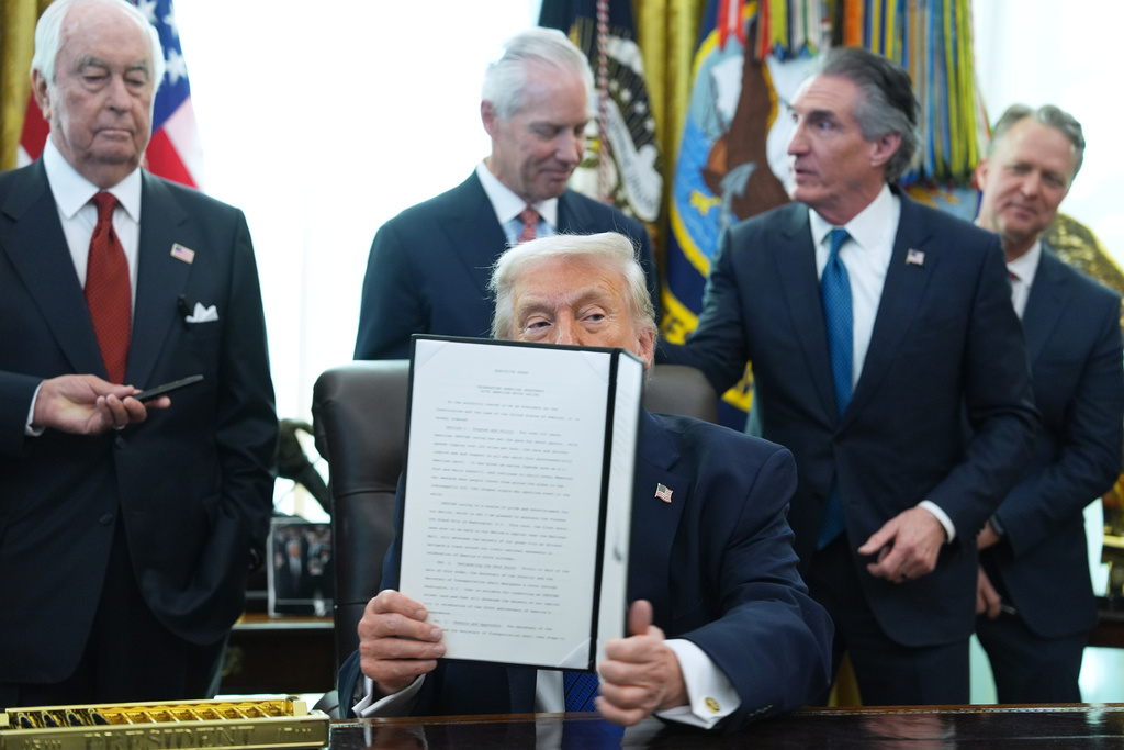 President Donald Trump holds an executive order he signed in the Oval Office of the White House, Friday, Jan. 30, 2026, in Washington. (AP Photo/Evan Vucci)
