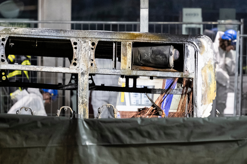 Fire investigators examine the charred shell of a bus that caught fire in Kerzers, Switzerland, Tuesday, March 10, 2026, killing several passengers and severely injuring several others, according to police. (Alessandro della Valle/Keystone via AP)
