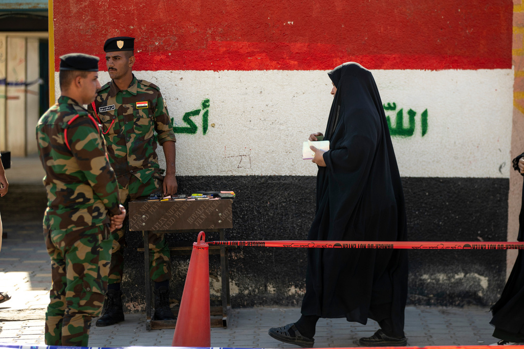 Iraqi police officers stand guard at a polling center as voters arrive to cast their ballots parliamentary elections in Najaf, Iraq, Tuesday, Nov. 11, 2025. (AP Photo/Anmar Khalil)