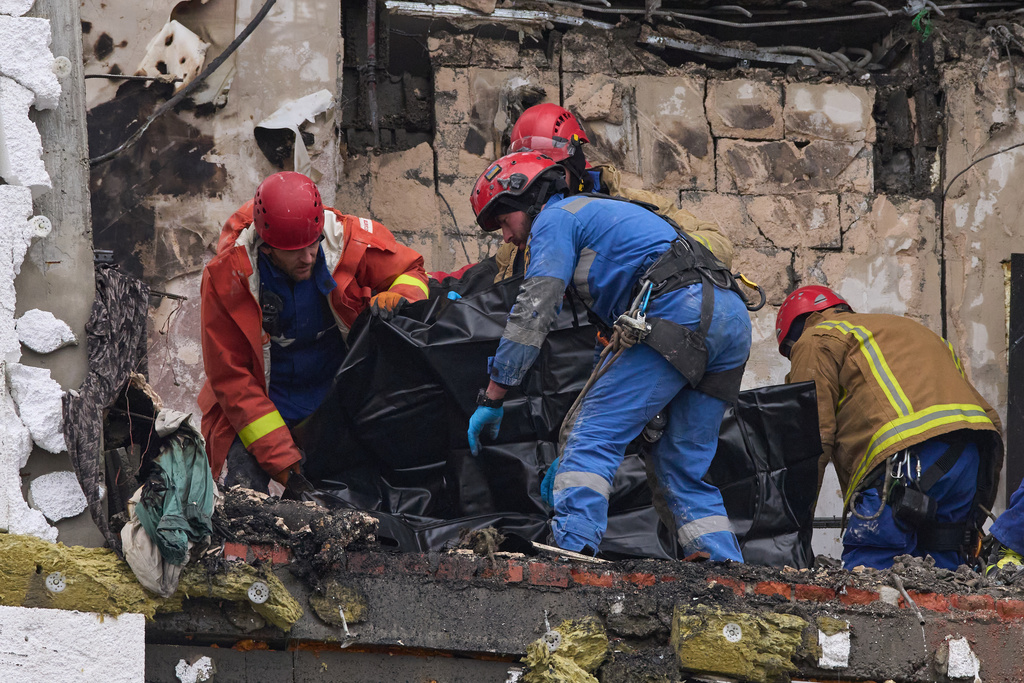 Rescuers put remains of a body of a victim into a plastic bag after Russian drone hit a multi-storey apartment building during massive missile and drone attack in Kyiv, Ukraine, Saturday, Dec. 27, 2025. (AP Photo/Efrem Lukatsky)