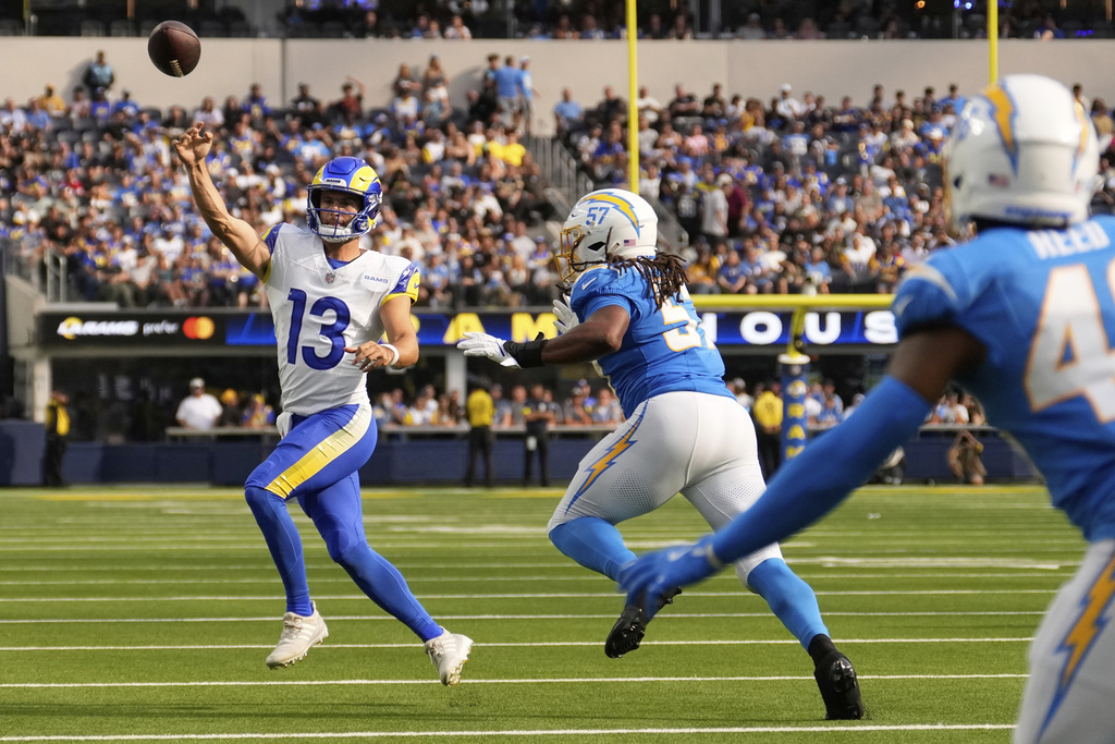 Los Angeles Rams quarterback Stetson Bennett IV (13) passes as Los Angeles Chargers linebacker Tre'Mon Morris-Brash (57) applies pressure during the first half of an NFL preseason football game, Saturday, Aug. 16, 2025, in Inglewood, Calif. (AP Photo/Mark J. Terrill)
