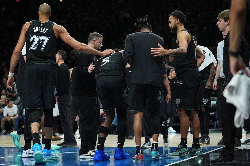 Minnesota Timberwolves guard Anthony Edwards (5) is helped off the court after sustaining an injury during the first half of Game 4 of a first-round NBA basketball playoff series against the Denver Nuggets, Saturday, April 25, 2026, in Minneapolis. (AP Photo/Abbie Parr)