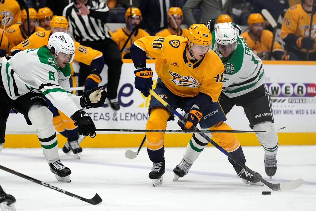 Nashville Predators center Fedor Svechkov (40) moves the puck ahead of Dallas Stars defenders Lian Bichsel (6) and Radek Faksa (12) during the second period of an NHL hockey game Saturday, Nov. 8, 2025, in Nashville, Tenn. (AP Photo/Mark Humphrey)