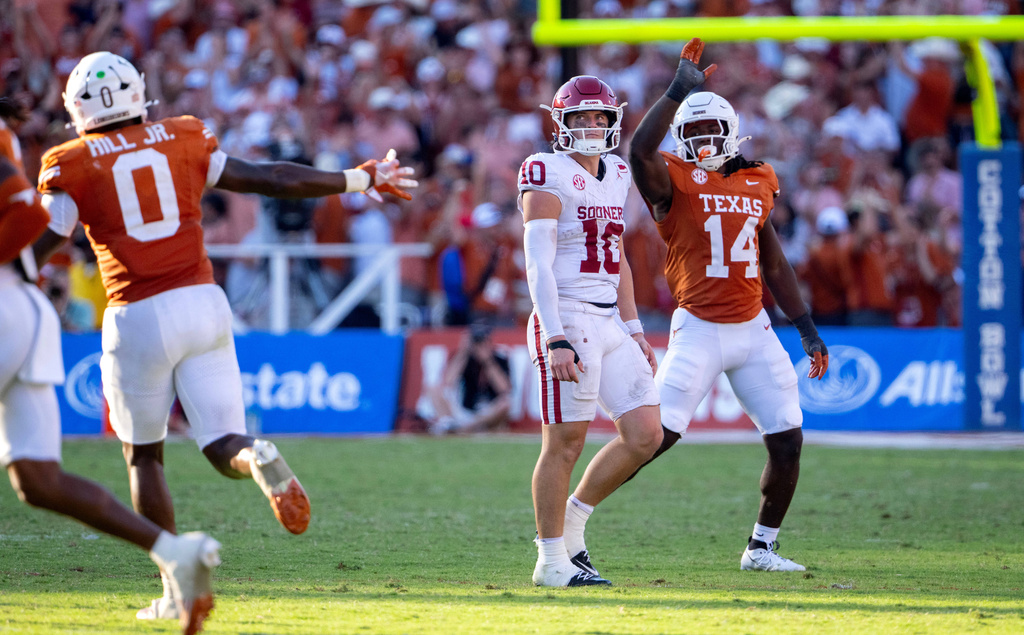 Texas linebacker Anthony Hill Jr. (0) and defensive end Brad Spence (14) react as Oklahoma quarterback John Mateer (10) walks off the field after failing to convert a fourth down during the second half of an NCAA college football game Saturday, Oct. 11, 2025, in Dallas. (AP Photo/Jeffrey McWhorter)
