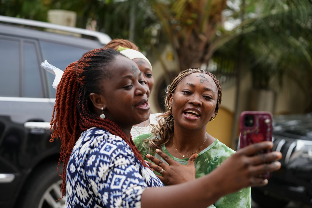 Catholic faithfuls with the sign of the cross in ash made on their forehead, takes a selfie and sing after a Mass to mark the beginning of Ash Wednesday at the church of the Assumption in Lagos, Nigeria, Wednesday, Feb. 18, 2026. (AP Photo/Sunday Alamba)