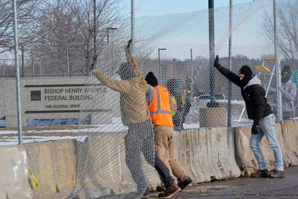 Masked workers put up fencing around the Bishop Whipple Federal Building, Monday, Jan. 12, 2026, in Minneapolis. (AP Photo/Jen Golbeck)