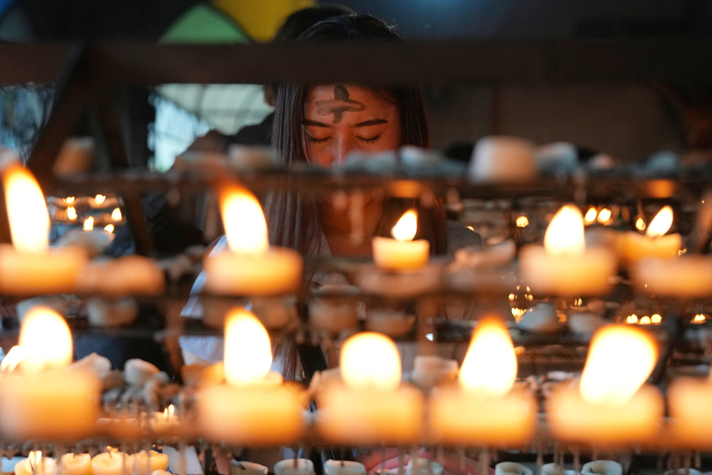 A devotee with ash cross on her forehead light candles during Ash Wednesday rites Wednesday, Feb. 18, 2026 at the Redemptorist Church in Manila, Philippines as Catholics in this predominantly Roman Catholic nation observe the start of lent. (AP Photo/Aaron Favila)
