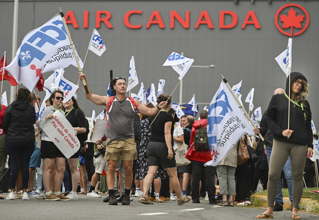 People protest outside Air Canada headquarters in Montreal, Sunday, Aug. 17, 2025, after the federal government is intervened in the labour dispute between the airline and the union representing its flight attendants, ordering binding arbitration and operations to resume. (Graham Hughes/The Canadian Press via AP)