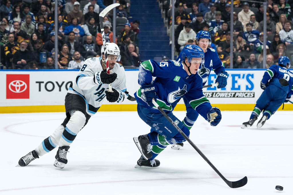 Utah Mammoth's Nick Schmaltz (8) pursues Vancouver Canucks' Elias Pettersson (25) who skates with the puck during the second period of an NHL hockey game in Vancouver, British Columbia, Friday, Dec. 5, 2025. (Ethan Cairns/The Canadian Press via AP)