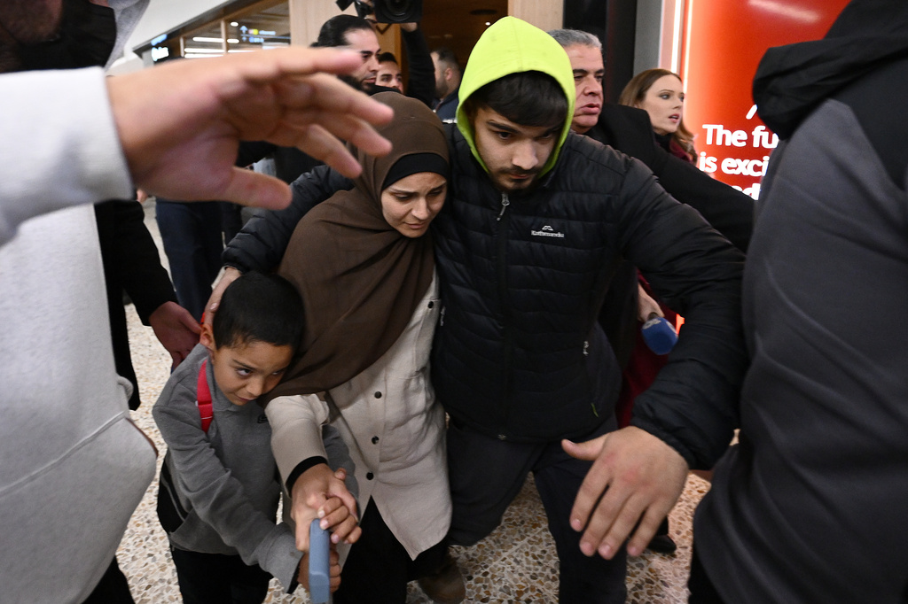 A group of supporters surround a woman with alleged ties to the Islamic State as she arrives with a child at Melbourne Airport, in Melbourne, Australia, Thursday, May 7, 2026. (Joel Carrett/AAP Image via AP)