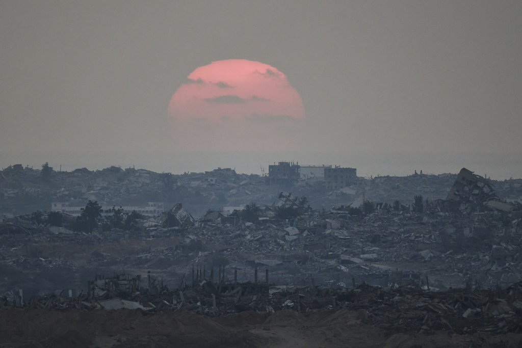 The sun sets behind buildings that were destroyed during the Israeli ground and air operations stand in the northern Gaza Strip as seen from southern Israel, Friday, Aug. 8, 2025. (AP Photo/Leo Correa)