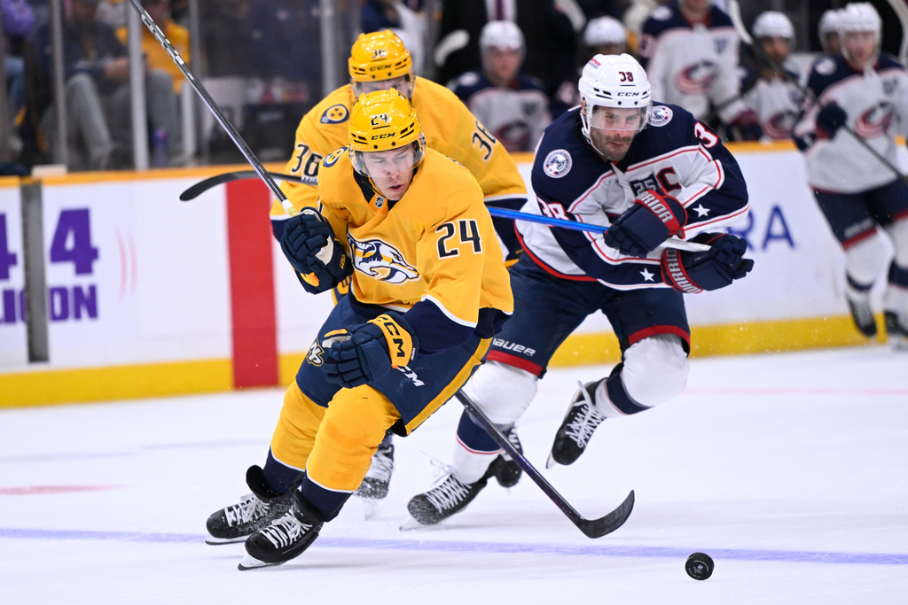 Nashville Predators defenseman Spencer Stastney (24) and Columbus Blue Jackets center Boone Jenner (38) vie for the puck during the first period of an NHL hockey game Thursday, Oct. 9, 2025, in Nashville, Tenn. (AP Photo/John Amis)