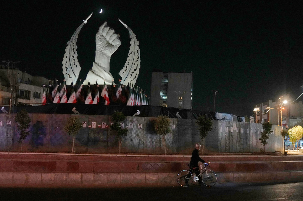 A man carries his bicycle in front of a monument depicting the clenched fist of the late Iranian Supreme Leader Ayatollah Ali Khamenei, who was killed in the U.S. and Israel strike on Feb. 28, in Islamic Revolution Square in Tehran, Sunday, July 19, 2026. (AP Photo/Vahid Salemi)
