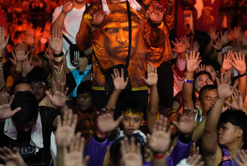 Catholic devotees raise their hands as a carriage carrying the image of Jesus Nazareno passes by during its annual procession in Manila, Philippines, on its feast day Friday Jan. 9, 2026. (AP Photo/Aaron Favila)