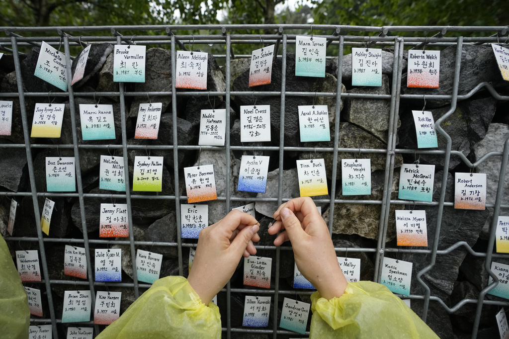 Eva-Lotta Margareta Glader, a Korean adoptee from Sweden, puts her nametag on The Wall of Names at Omma Poom Park in Paju, South Korea, on May 20, 2026. (AP Photo/Ahn Young-joon)