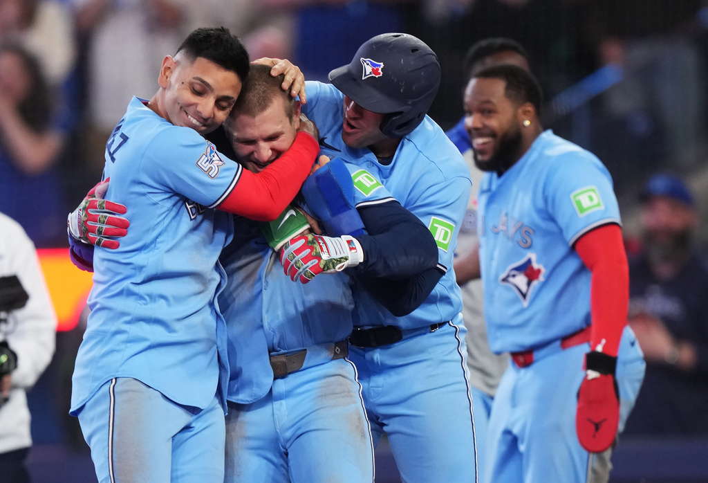 Toronto Blue Jays' Daulton Varsho (second left) celebrates his walk-off grand slam against the Tampa Bay Rays with Andres Gimenez (left) and George Springer during 10th inning MLB baseball action in Toronto on Wednesday, May 13, 2026. (Nathan Denette/The Canadian Press via AP)