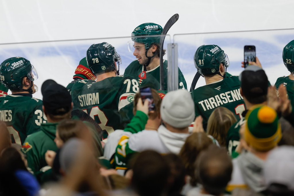 Minnesota Wild defenseman Quinn Hughes, center, is congratulated after scoring during the third period of an NHL hockey game against the Boston Bruins, Sunday, Dec. 14, 2025, in St. Paul, Minn. (AP Photo/Bailey Hillesheim)