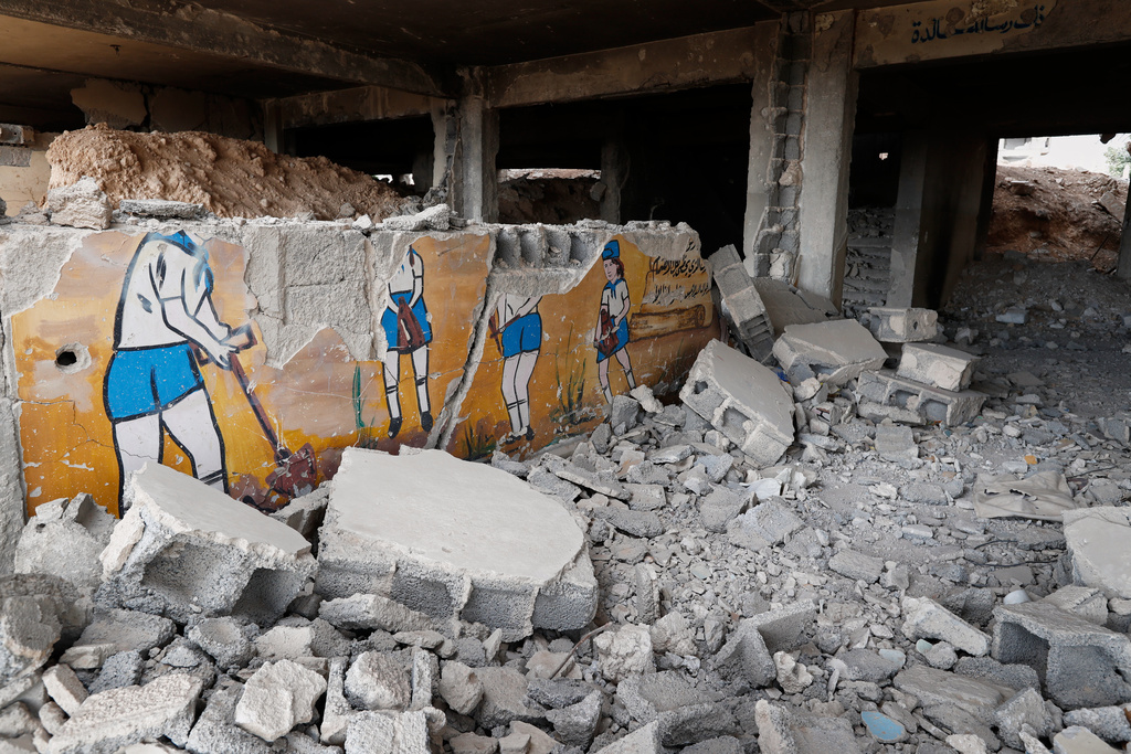 A mural on the wall depicting students from the Baath Youth Organization appears at the entrance of a school destroyed during the fighting between forces loyal to former President Bashar Assad and rebel groups, in the devastated Jobar neighborhood of Damascus, Syria, Thursday, Sept. 25, 2025. (AP Photo/Omar Sanadiki)