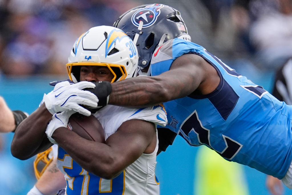 Los Angeles Chargers running back Kimani Vidal (30) is tackled by Tennessee Titans linebacker Jaylen Harrell (92) during the first half of an NFL football game Sunday, Nov. 2, 2025, in Nashville, Tenn. (AP Photo/George Walker IV)