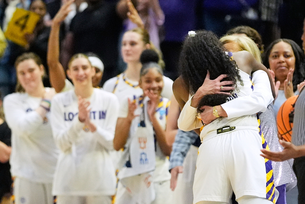 LSU guard Flau'jae Johnson (4) hugs head coach Kim Mulkey as she is pulled during her last home game during the second half in the second round of the NCAA college basketball tournament against Texas Tech, Sunday, March 22, 2026, in Baton Rouge, La. (AP Photo/Gerald Herbert)