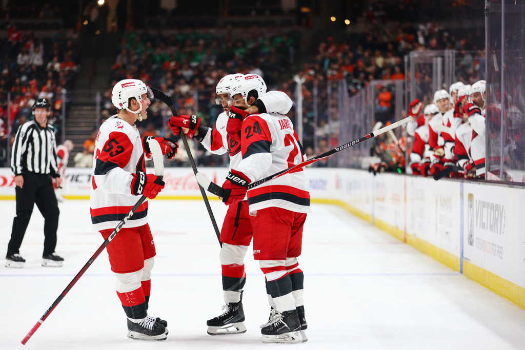 Carolina Hurricanes players embrace Carolina Hurricanes center Seth Jarvis (24) after scoring during the second period of an NHL hockey game Thursday, Oct. 16, 2025, in Anaheim, Calif. (AP Photo/Ethan Swope)