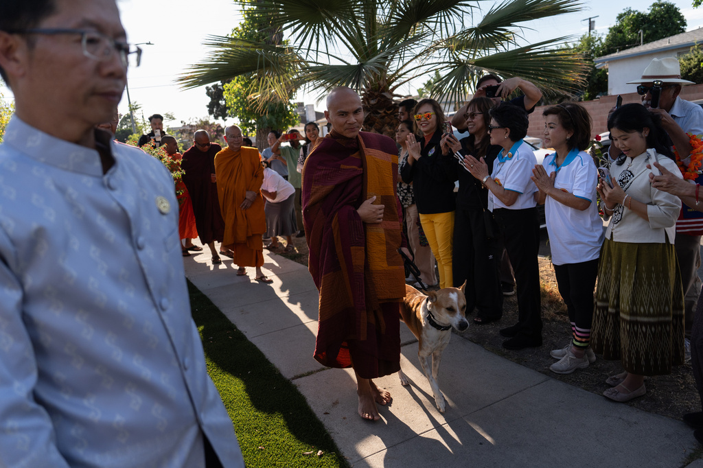 Bhikkhu Pannakara, a Buddhist monk who led a Walk for Peace from Fort Worth, Texas, to Washington, D.C., and his dog, Aloka, are greeted by well-wishers during an event at Wat Thai of Los Angeles in the North Hollywood section of Los Angeles, Monday, July 13, 2026. (AP Photo/Jae C. Hong)