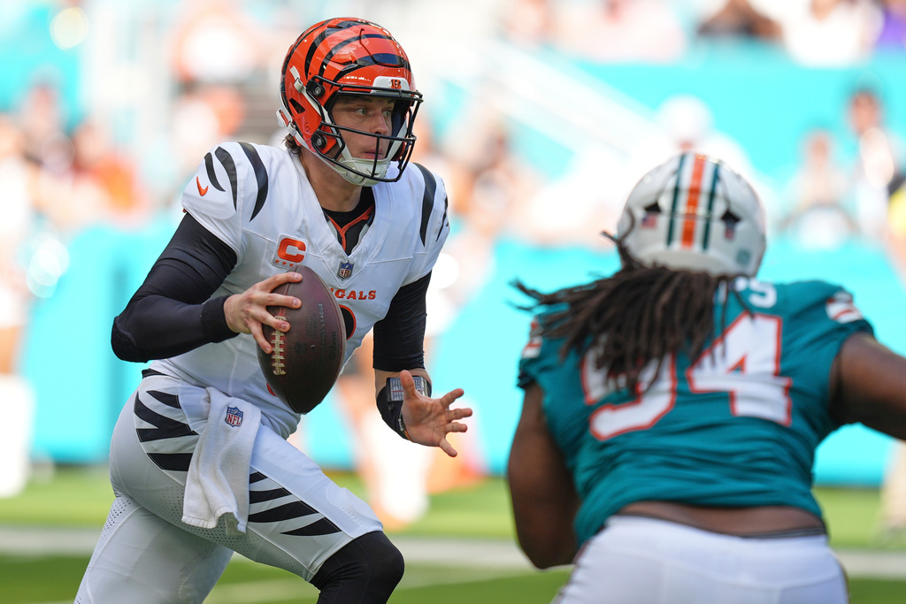 Cincinnati Bengals quarterback Joe Burrow, left, scrambles during the first half of an NFL football game against the Miami Dolphins, Sunday, Dec. 21, 2025, in Miami Gardens, Fla. (AP Photo/Rebecca Blackwell)