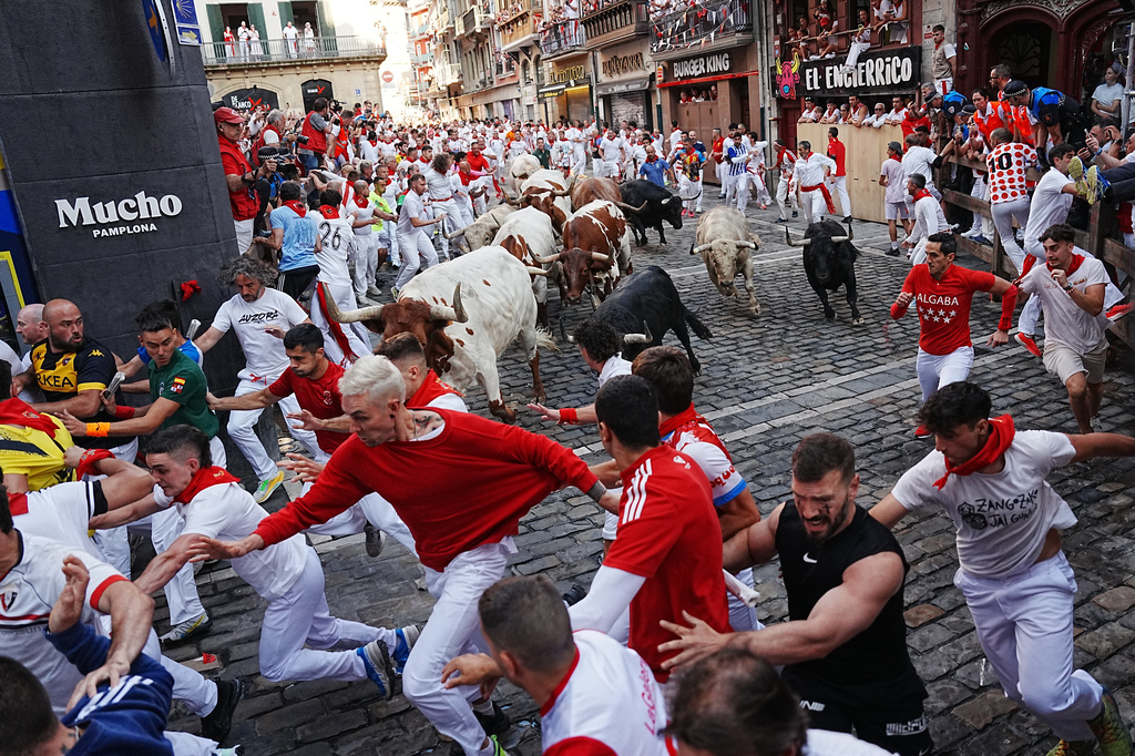 Revelers run alongside Fuente Ymbro's fighting bulls during the first running of the bulls at the San Fermín festival in Pamplona, Spain, Tuesday, July 7, 2026. (AP Photo/Miguel Oses)