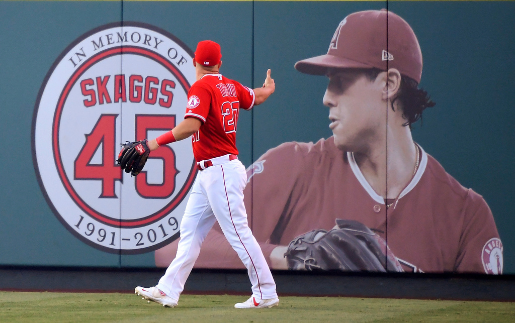 FILE - Los Angeles Angels center fielder Mike Trout gestures toward a photo of Tyler Skaggs in center field prior to a baseball game against the Detroit Tigers in Anaheim, Calif., on July 29, 2019. (AP Photo/Mark J. Terrill, File)