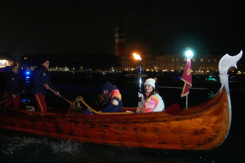 A torchbearer holds an Olympic torch flame on the Grand Canal in Venice, Italy, Thursday, Jan. 22, 2026, its journey will conclude in Milan on February 6 for the Winter Olympics opening ceremony. (AP Photo/Luca Bruno)