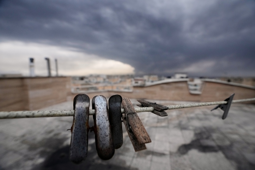 Clothes clips covered in soot from burned fuel are seen as smoke from a U.S.-Israeli strike on an oil facility late Saturday lingers in the cloudy sky over Tehran, Iran, Sunday, March 8, 2026. (AP Photo/Vahid Salemi)