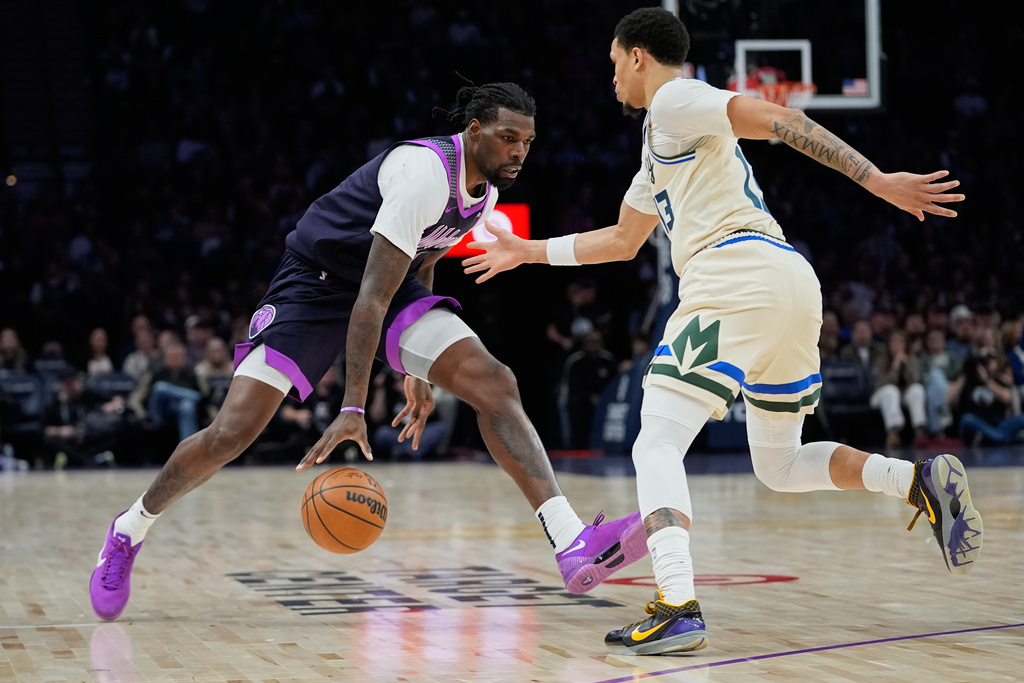 Minnesota Timberwolves center Naz Reid, left, works toward the basket as Milwaukee Bucks guard Ryan Rollins defends during the first half of an NBA basketball game, Sunday, Dec. 21, 2025, in Minneapolis. (AP Photo/Abbie Parr)
