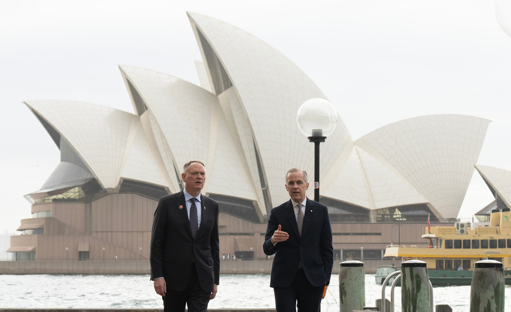 Canada's Defence Minister David McGuinty, left, talks with Canada's Prime Minister Mark Carney as they walk to a news conference, in Sydney, Australia, Wednesday, March 4, 2026. (Adrian Wyld/The Canadian Press via AP)