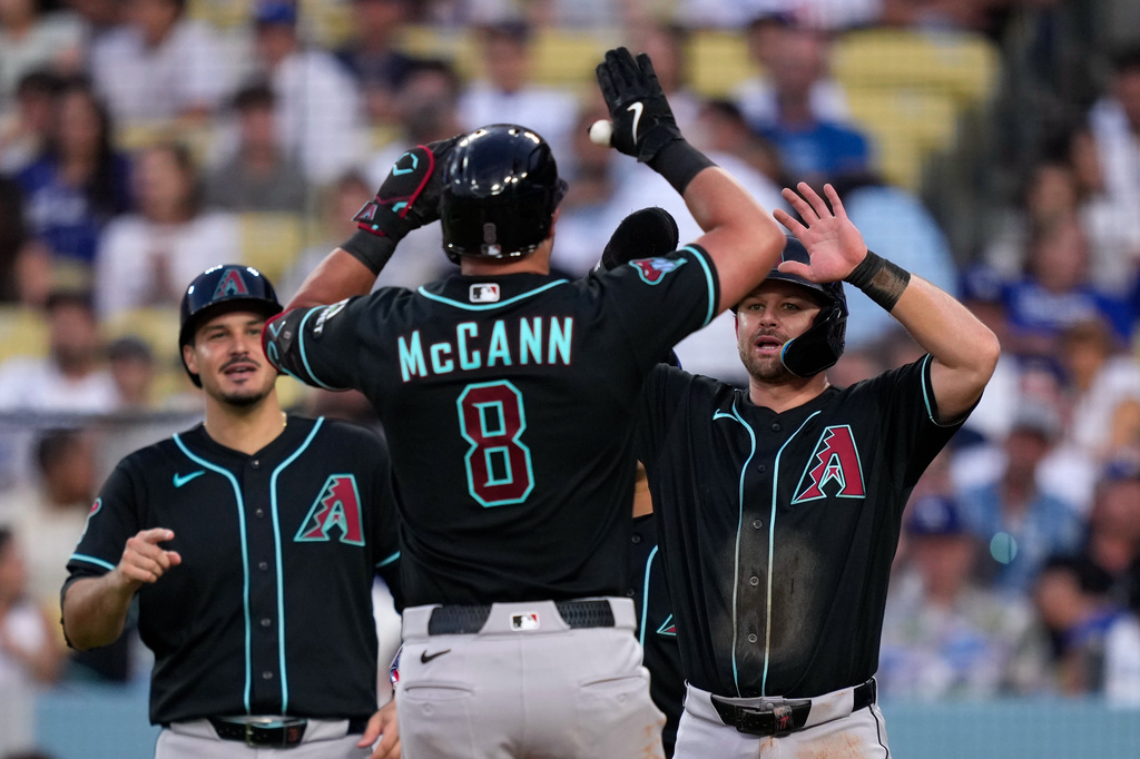 Arizona Diamondbacks' James McCann, center, is congratulated by Nolan Arenado, left, and Tim Tawa after hitting a three-run home run during the sixth inning of a baseball game against the Los Angeles Dodgers, Saturday, July 11, 2026, in Los Angeles. (AP Photo/Mark J. Terrill)