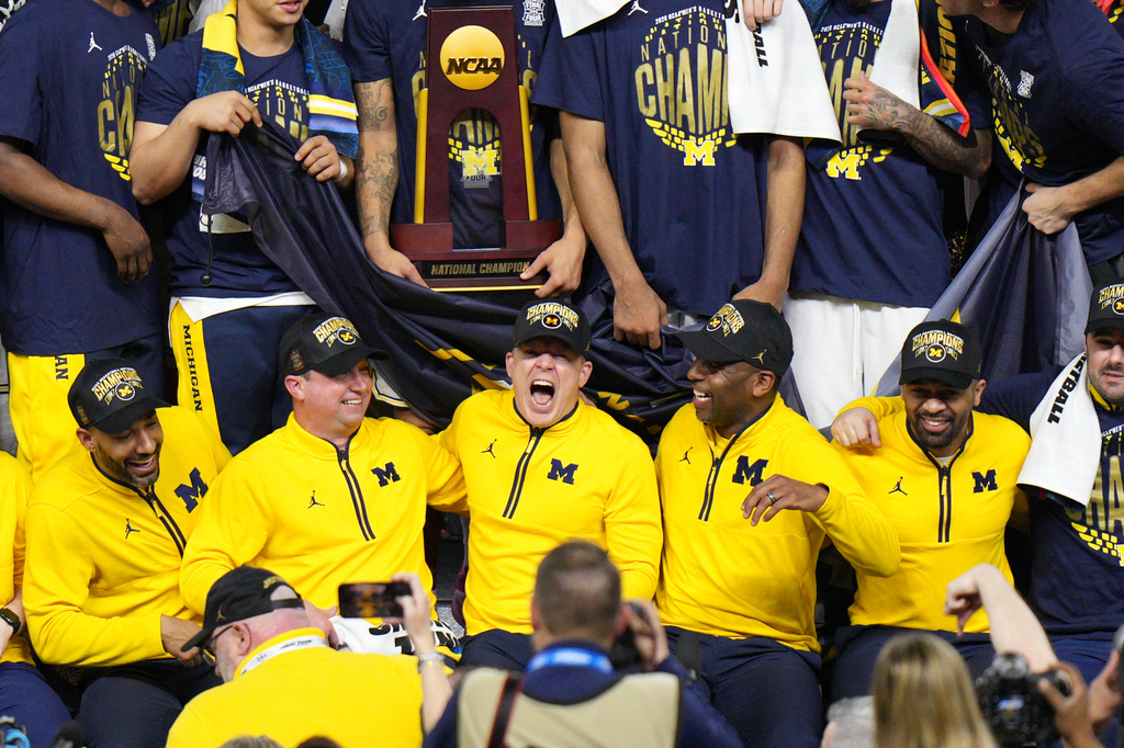 Michigan head coach Dusty May, center, celebrates with his team after defeating UConn in the NCAA college basketball tournament national championship game at the Final Four, Monday, April 6, 2026, in Indianapolis. (AP Photo/AJ Mast)