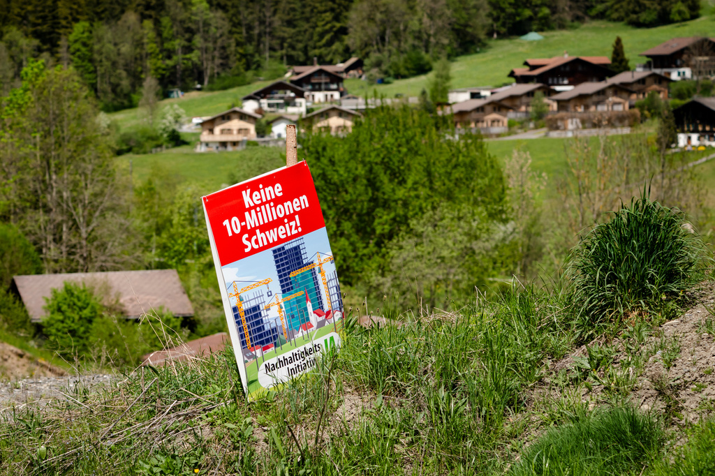 An electoral poster for the right-wing Swiss People's Party (SVP) popular initiative "No 10-million-Switzerland" is pictured on a field, near Zweisimmen, Switzerland, May 2, 2026. (Jean-Christophe Bott/Keystone via AP)