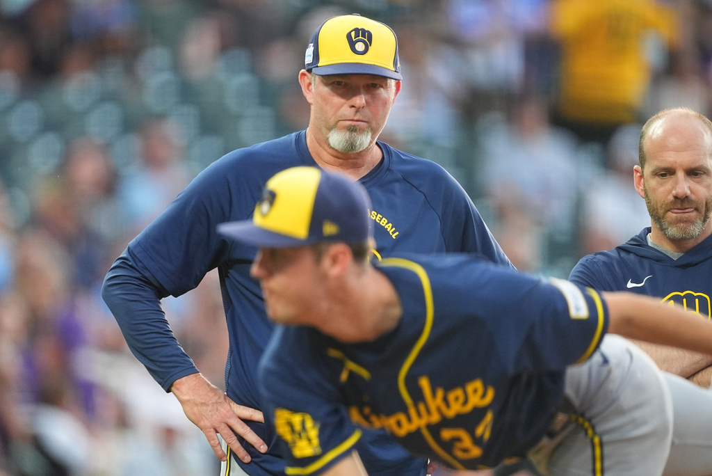 Milwaukee Brewers pitching coach Chris Hook, top left, looks on as starter Jacob Misiorowski, foreground, throws a practice pitch after being hit by a single off the bat of Colorado Rockies' Troy Johnston in the second inning of a baseball game Saturday, June 6, 2026, in Denver. (AP Photo/David Zalubowski)