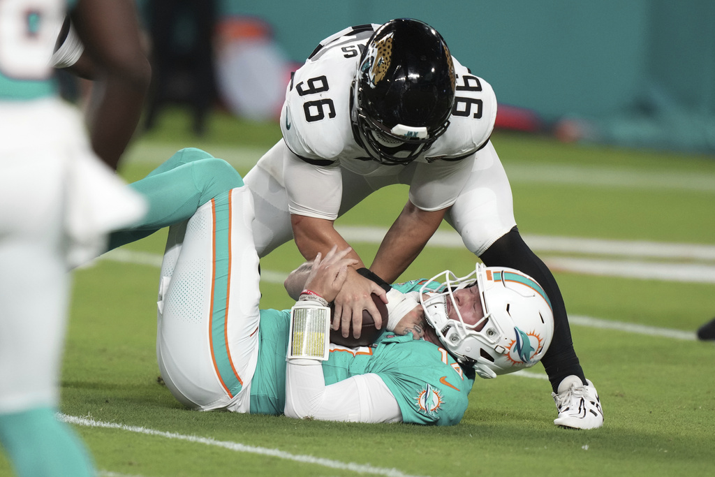 Miami Dolphins quarterback Quinn Ewers (14) is sacked by Jacksonville Jaguars defensive end Ethan Downs (96) during the second half of an NFL preseason football game, Saturday, Aug. 23, 2025, in Miami Gardens, Fla. (AP Photo/Lynne Sladky)