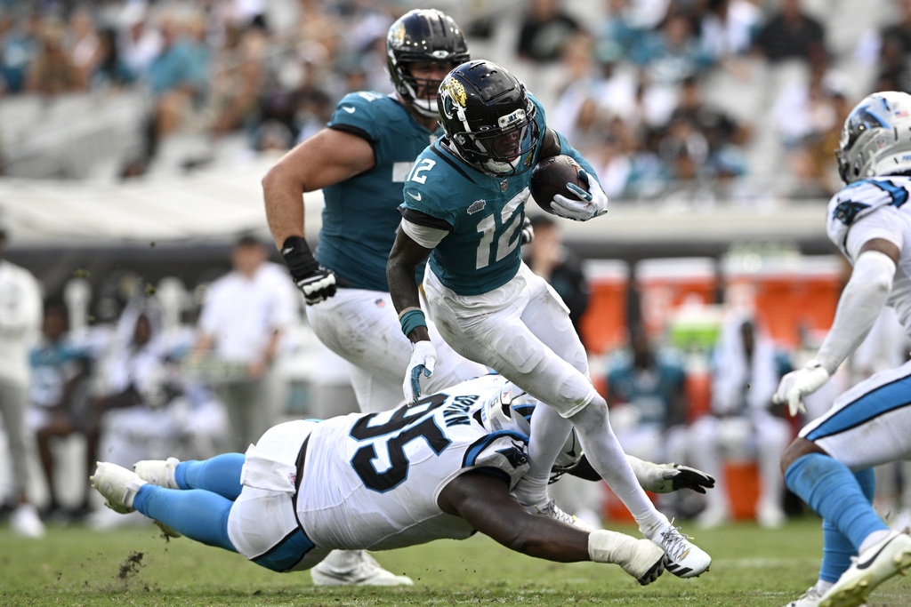Jacksonville Jaguars wide receiver Travis Hunter (12) runs with the ball against Carolina Panthers defensive end Derrick Brown (95) during the second half of an NFL football game, Sunday, Sept. 7, 2025, in Jacksonville, Fla. (AP Photo/Phelan M. Ebenhack)