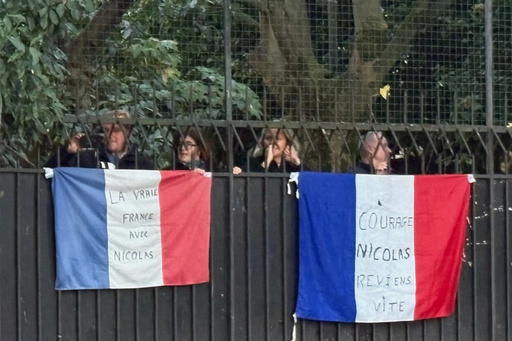 People stand behind French flags with inscription reading "Courage Nicolas, come back soon", right, and "True France with Nicolas" outside former French President Nicolas Sarkozy's home, Tuesday, Oct. 21, 2025 in Paris. Former French President Nicolas Sarkozy heads to prison to serve time for a criminal conspiracy to finance his 2007 election campaign with funds from Libya. (AP Photo/Masha Macpherson) People stand behind French flags with inscription reading "Courage Nicolas, come back soon", right, and "True France with Nicolas" outside former French President Nicolas Sarkozy's home, Tuesday, Oct. 21, 2025 in Paris. Former French President Nicolas Sarkozy heads to prison to serve time for a criminal conspiracy to finance his 2007 election campaign with funds from Libya. (AP Photo/Masha Macpherson)