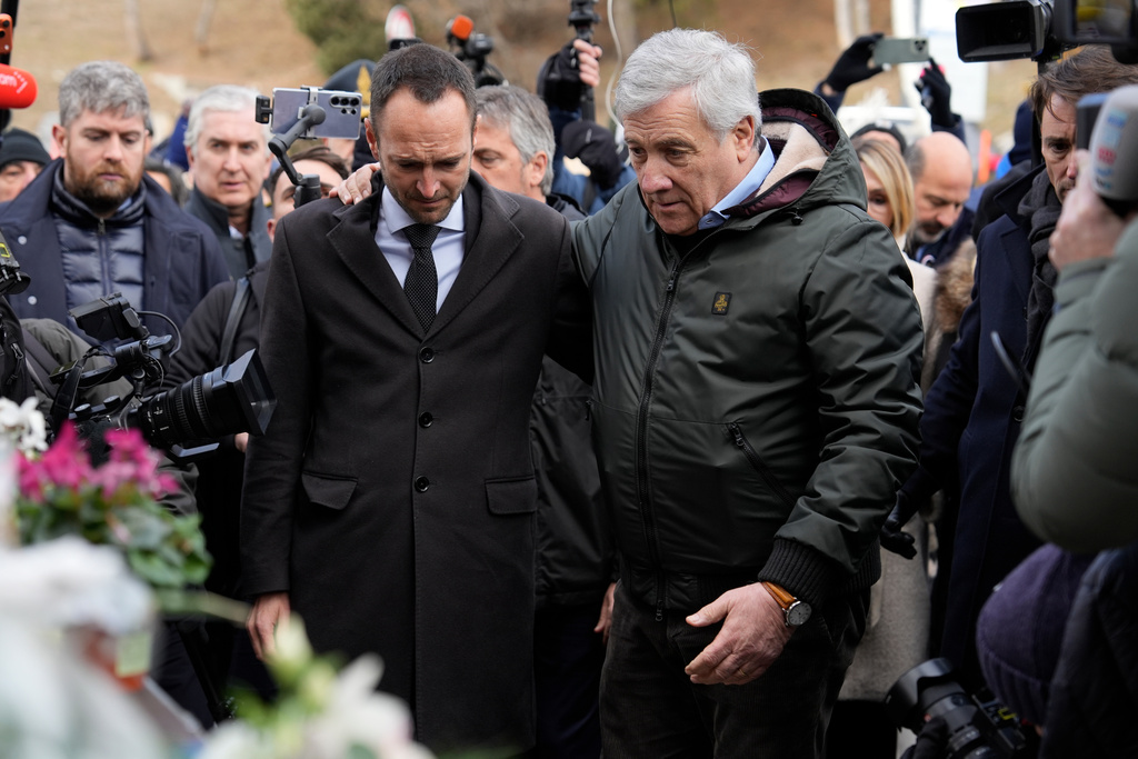 Italian Foreign Minister Antonio Tajani, right, and Valais regional government Mathias Reynard pay tribute at the sealed off Le Constellation bar, where a devastating fire left dead and injured during the New Year's celebrations in Crans-Montana, Swiss Alps, Switzerland, Friday, Jan. 2, 2026. (AP Photo/Baz Ratner)
