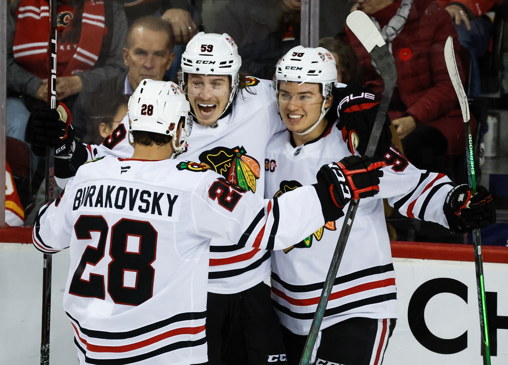 Chicago Blackhawks' Tyler Bertuzzi, centre, celebrates his goal with teammates Andre Burakovsky, left, and Connor Bedard during third period NHL hockey action against the Calgary Flames in Calgary, Friday, Nov. 7, 2025. (Jeff McIntosh/The Canadian Press via AP)