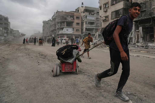 Displaced Palestinians walk with their belongings along the heavily damaged Al-Jalaa Street in Gaza City, Sunday, Oct. 12, 2025, after Israel and Hamas agreed to a pause in their war and the release of the remaining hostages. (AP Photo/Abdel Kareem Hana) Displaced Palestinians walk with their belongings along the heavily damaged Al-Jalaa Street in Gaza City, Sunday, Oct. 12, 2025, after Israel and Hamas agreed to a pause in their war and the release of the remaining hostages. (AP Photo/Abdel Kareem Hana)