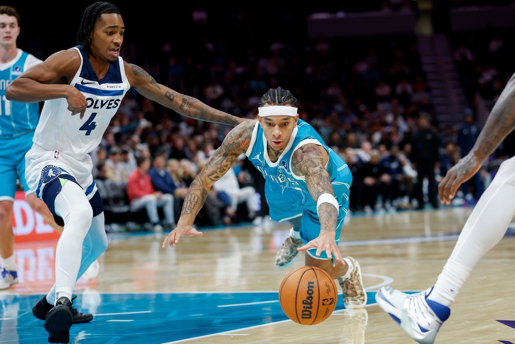Charlotte Hornets guard Tre Mann dives for a loose ball against Minnesota Timberwolves guard Rob Dillingham (4) during the second half of an NBA basketball game in Charlotte, N.C., Saturday, Nov. 1, 2025. (AP Photo/Nell Redmond)