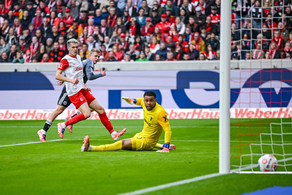 Eintracht Frankfurt's Jonathan Burkardt scores a goal past Freiburg's goalkeeper Noah Atubolu, during a German Bundesliga soccer match between SC Freiburg and Eintracht Frankfurt, in Freiburg im Breisgau, Germany, Sunday, Oct. 19, 2025. (Harry Langer/dpa via AP)