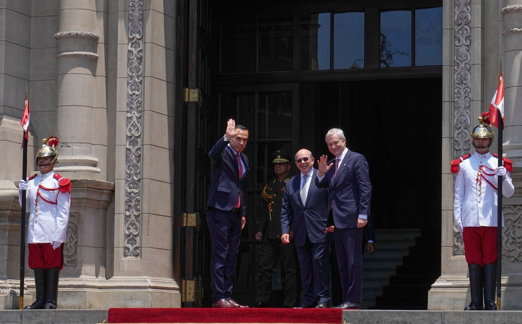 Peru's President Jose Jeri, left, and Chile's President-elect Jose Antonio Kast, right, wave to the press as Kast arrives at the government palace in Lima, Peru, Wednesday, Jan. 7, 2026. (AP Photo/Martin Mejia)