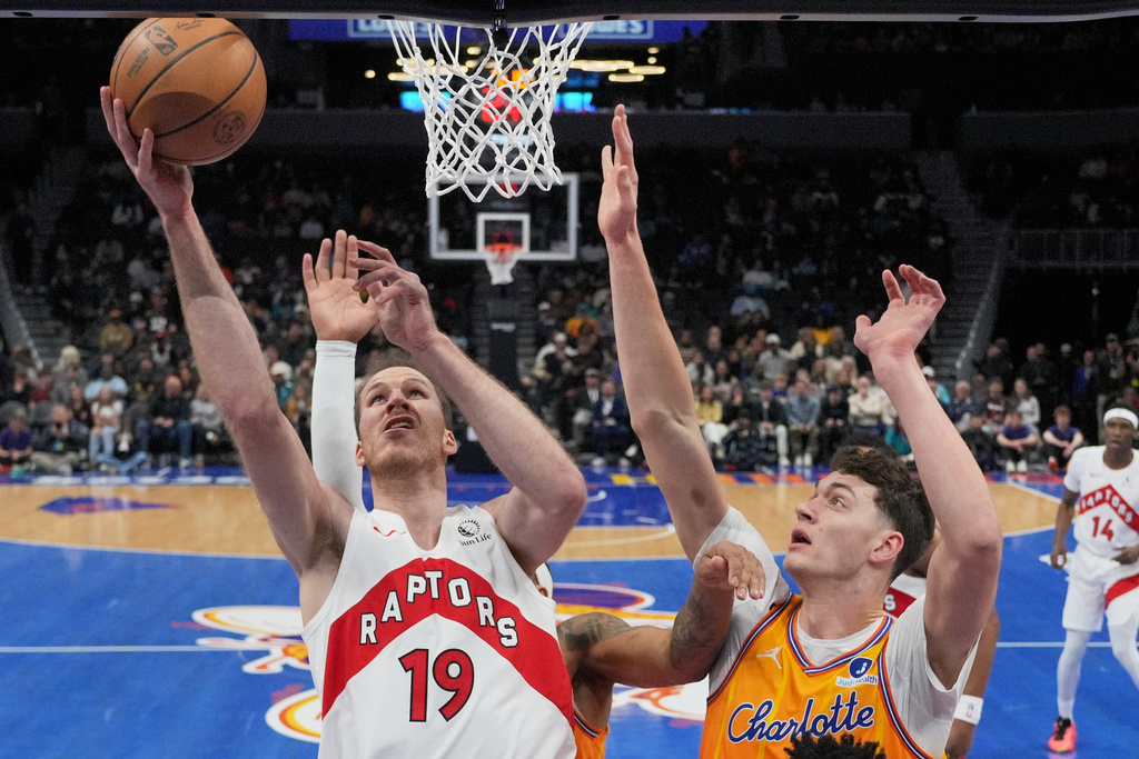 Toronto Raptors center Jakob Poeltl shoots over Charlotte Hornets center Ryan Kalkbrenner during the first half of an NBA basketball game, Saturday, Nov. 29, 2025, in Charlotte, N.C. (AP Photo/Chris Carlson)